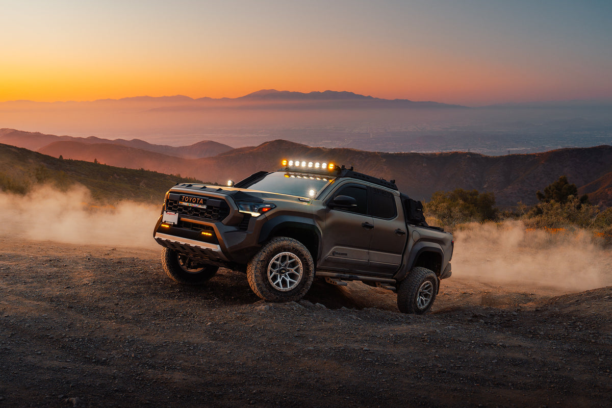 Rocktrix RT107 wheels in Machined Silver on a Toyota Tacoma Trailhunter at sunset on a mountain road